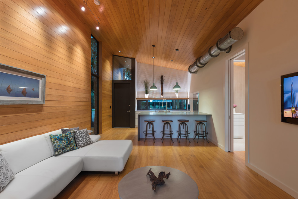 Photo of a small contemporary open concept living room in Other with multi-coloured walls, no fireplace, a wall-mounted tv, light hardwood floors, brown floor, wood and planked wall panelling.