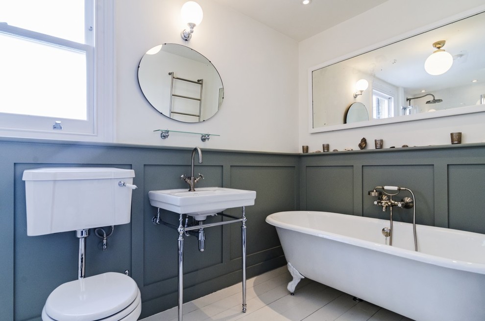 Mid-sized traditional bathroom in London with a console sink, recessed-panel cabinets, grey cabinets, wood benchtops, a claw-foot tub, an alcove shower, a two-piece toilet, white tile, porcelain tile, white walls and painted wood floors.