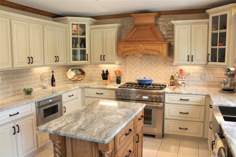 Photo of a large traditional u-shaped eat-in kitchen in Detroit with an undermount sink, raised-panel cabinets, beige cabinets, quartzite benchtops, beige splashback, ceramic splashback, stainless steel appliances, ceramic floors, with island, beige floor and beige benchtop.