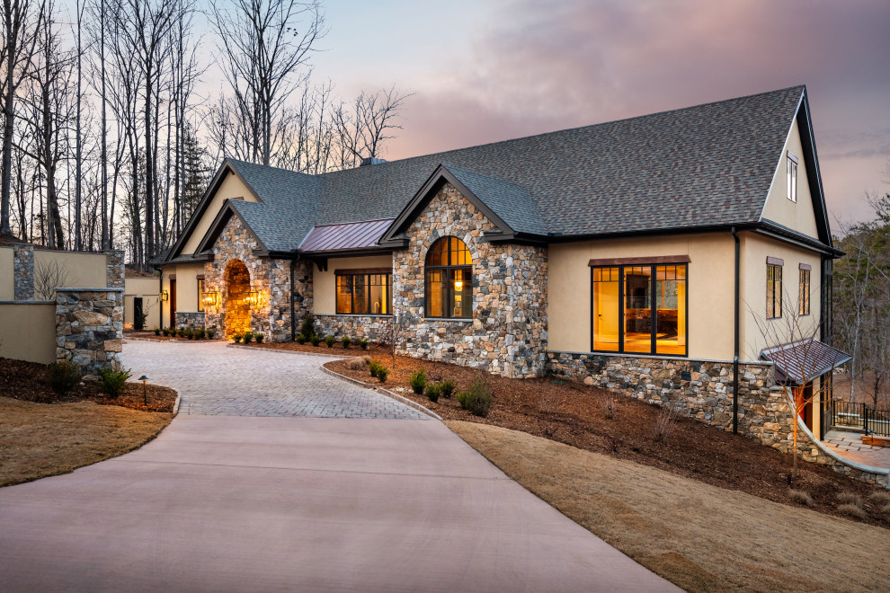 Example of a large transitional beige two-story stone house exterior design with a gambrel roof, a mixed material roof and a gray roof