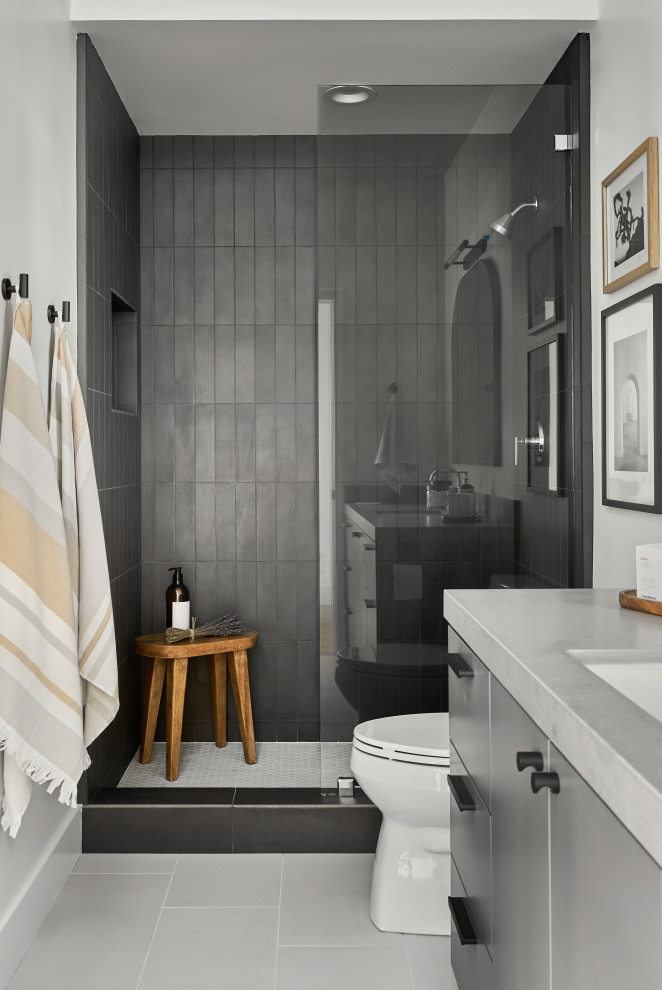 Bild på ett mellanstort funkis grå grått badrum med dusch, med släta luckor, grå skåp, en dusch i en alkov, en toalettstol med separat cisternkåpa, svart kakel, porslinskakel, vita väggar, klinkergolv i keramik, ett undermonterad handfat, bänkskiva i kvarts, grått golv och med dusch som är öppen
