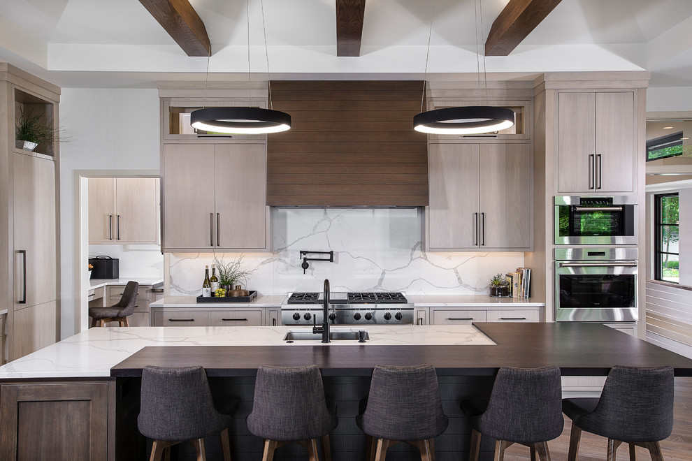 Photo of an expansive modern l-shaped open plan kitchen in Grand Rapids with an undermount sink, flat-panel cabinets, light wood cabinets, white splashback, marble splashback, stainless steel appliances, with island, brown floor, quartzite benchtops, dark hardwood floors and white benchtop.