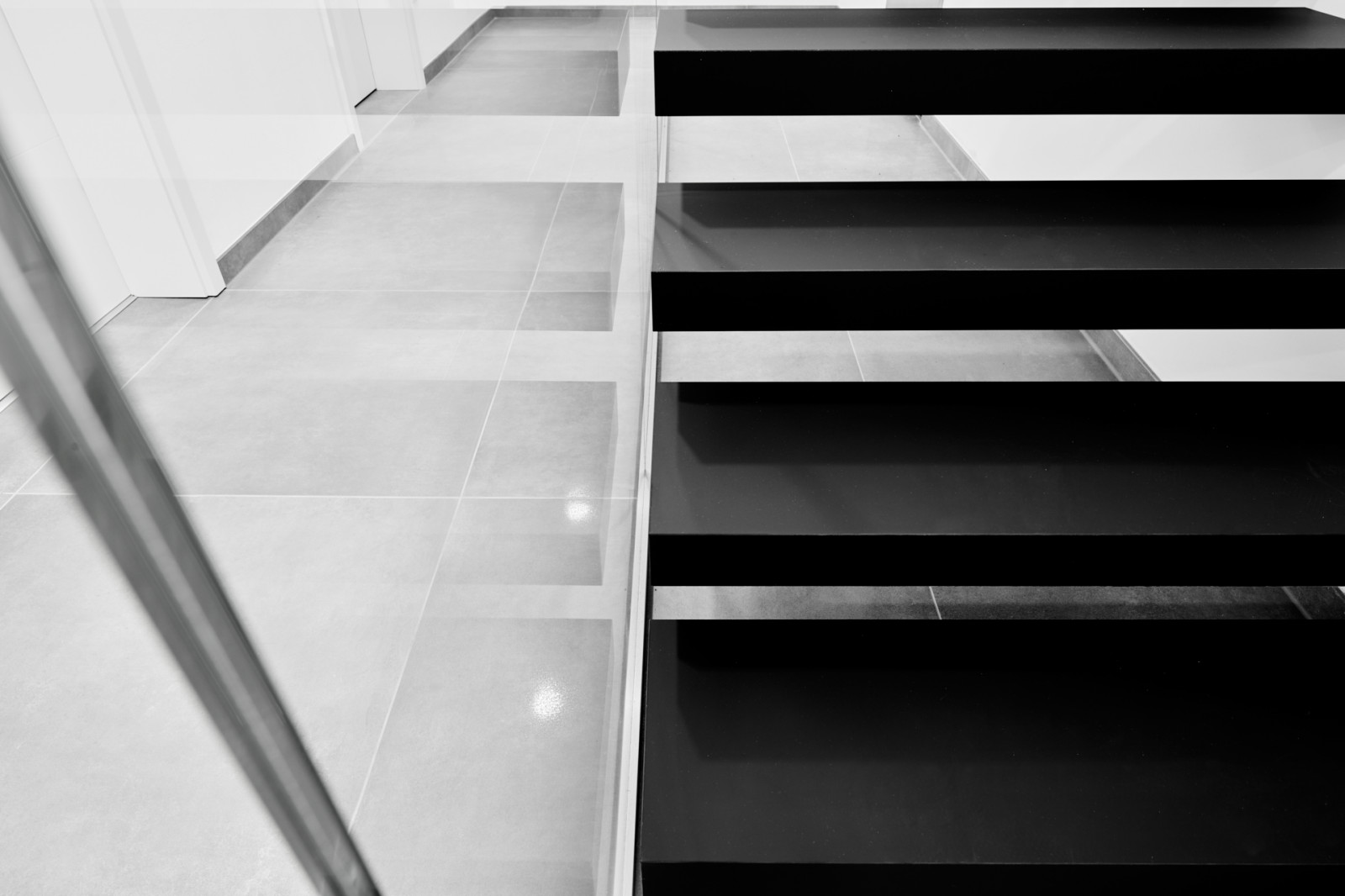 Консольная лестница в черном матовом цвете с ограждением из белого стекла