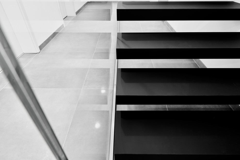 Консольная лестница в черном матовом цвете с ограждением из белого стекла