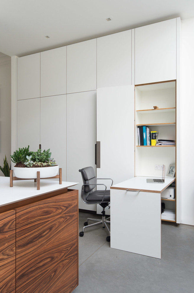 Photo of a contemporary study room in London with white walls, concrete floors and a built-in desk.