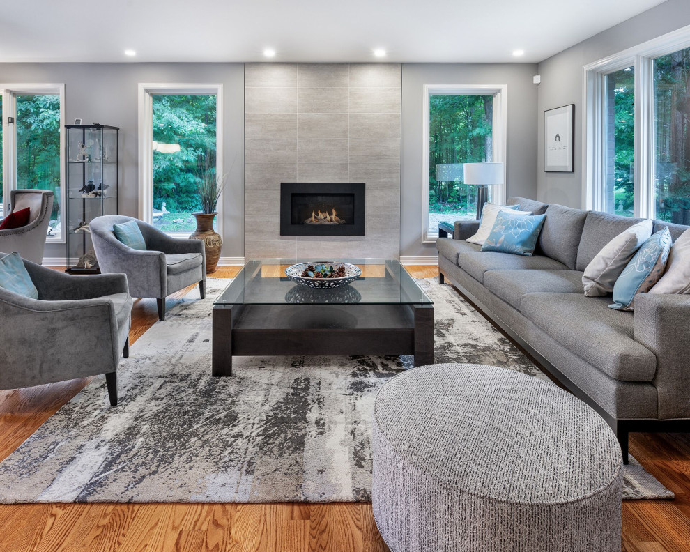 Transitional living room in Other with grey walls, medium hardwood floors, a standard fireplace and a tile fireplace surround.
