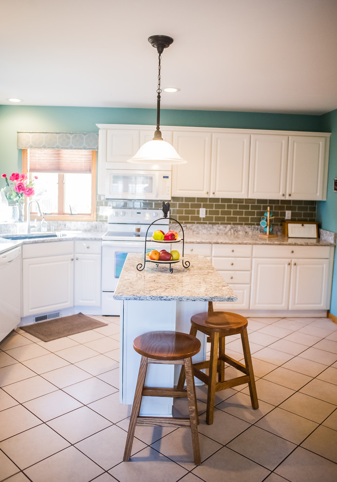 Small transitional u-shaped ceramic tile eat-in kitchen photo with a drop-in sink, raised-panel cabinets, white cabinets, granite countertops, brown backsplash, porcelain backsplash, white appliances and an island
