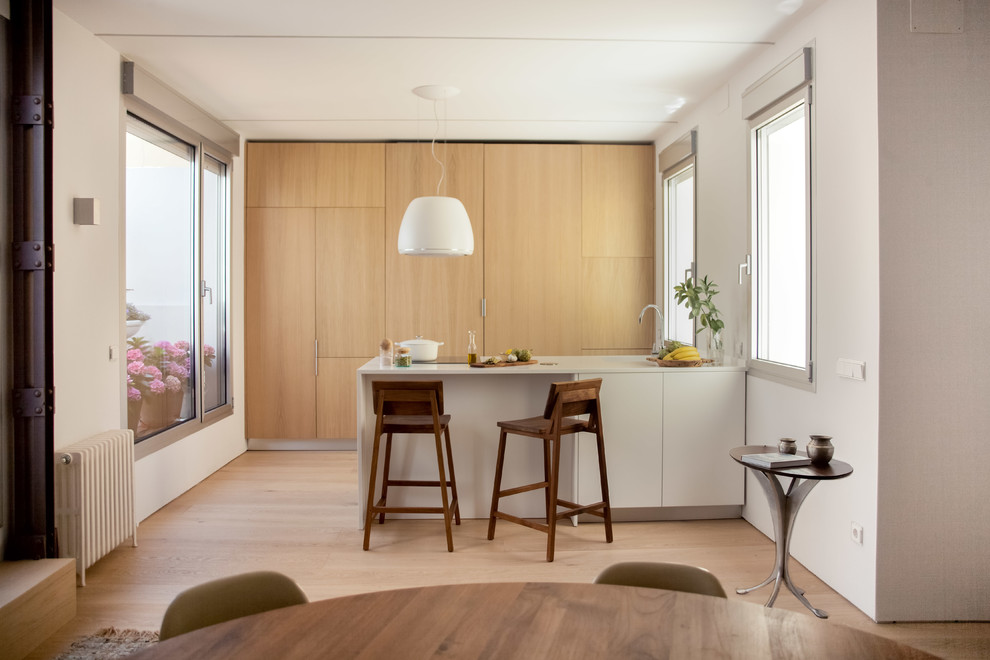 This is an example of a mid-sized contemporary galley eat-in kitchen in Berlin with flat-panel cabinets, medium wood cabinets, panelled appliances, light hardwood floors, beige floor, a peninsula, a drop-in sink, wood benchtops, brown splashback and timber splashback.