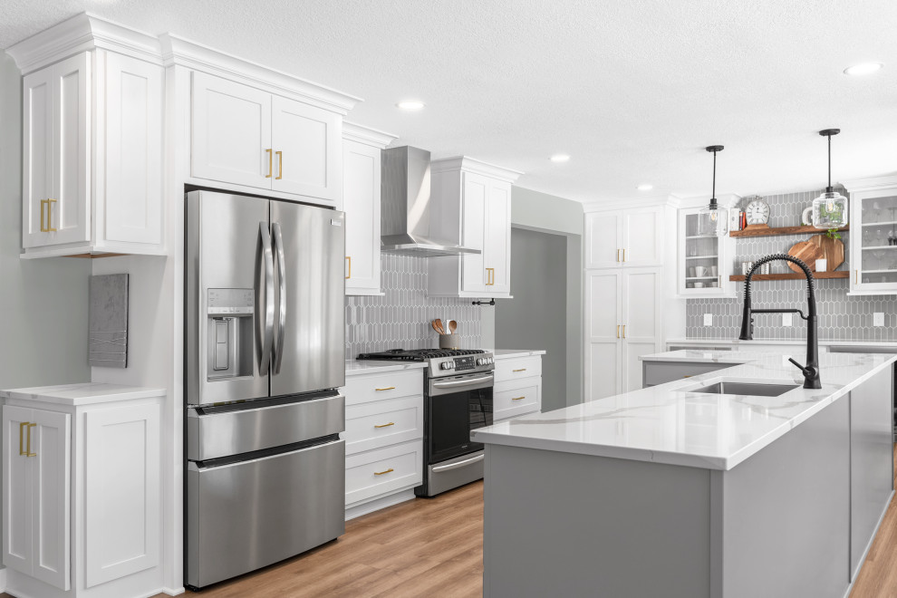 Example of a mid-sized transitional l-shaped light wood floor and brown floor eat-in kitchen design in Minneapolis with an undermount sink, recessed-panel cabinets, gray cabinets, quartz countertops, gray backsplash, glass tile backsplash, stainless steel appliances, an island and white countertops