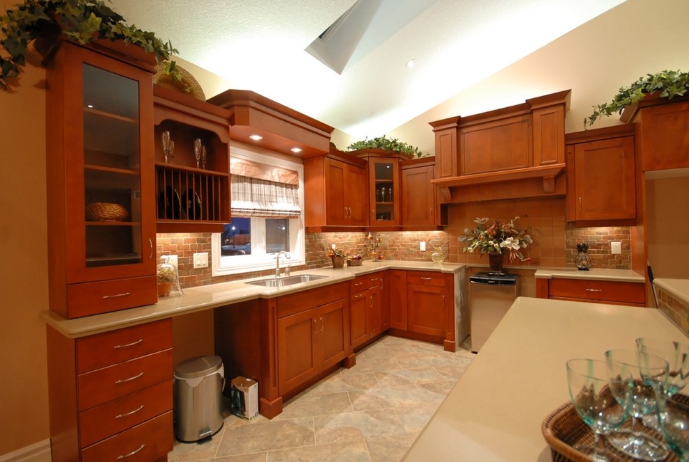 Inspiration for a mid-sized l-shaped ceramic tile enclosed kitchen remodel with an undermount sink, shaker cabinets, medium tone wood cabinets, brown backsplash, subway tile backsplash, stainless steel appliances and an island