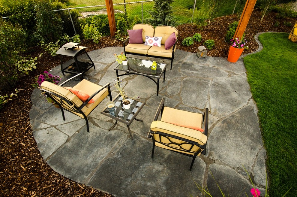 Design ideas for a contemporary backyard patio in Calgary with natural stone pavers.