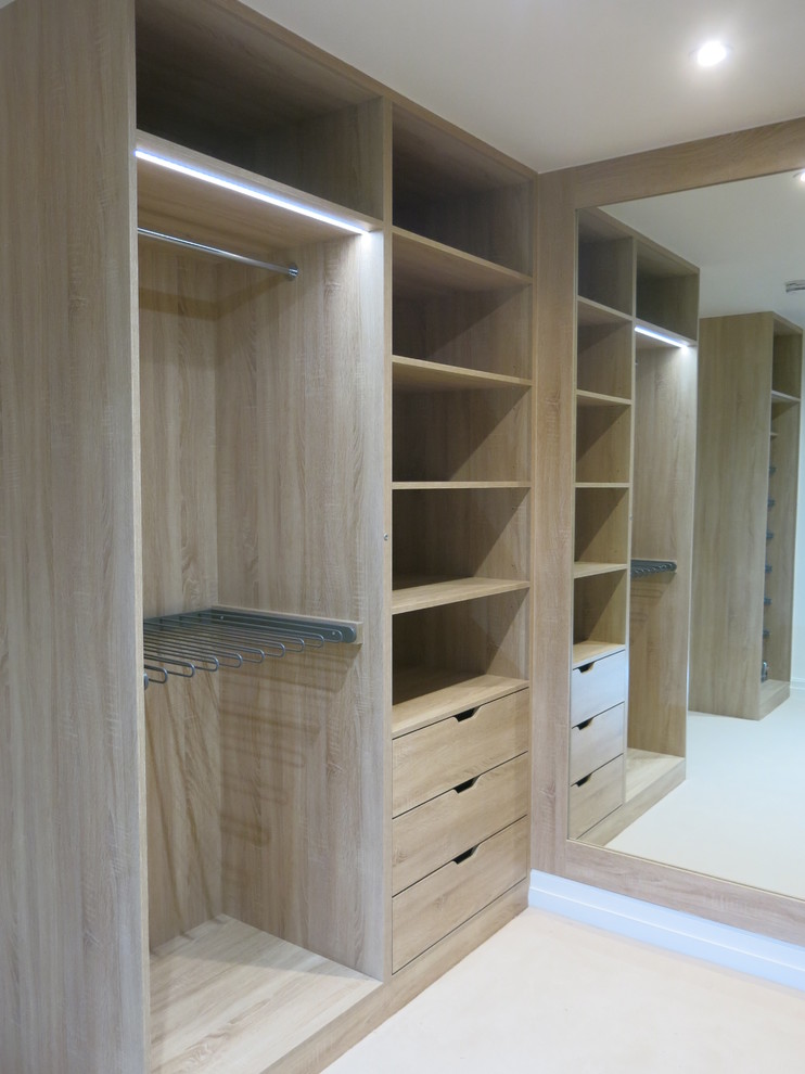 Design ideas for a large gender-neutral walk-in wardrobe in London with open cabinets, light wood cabinets, carpet and beige floor.