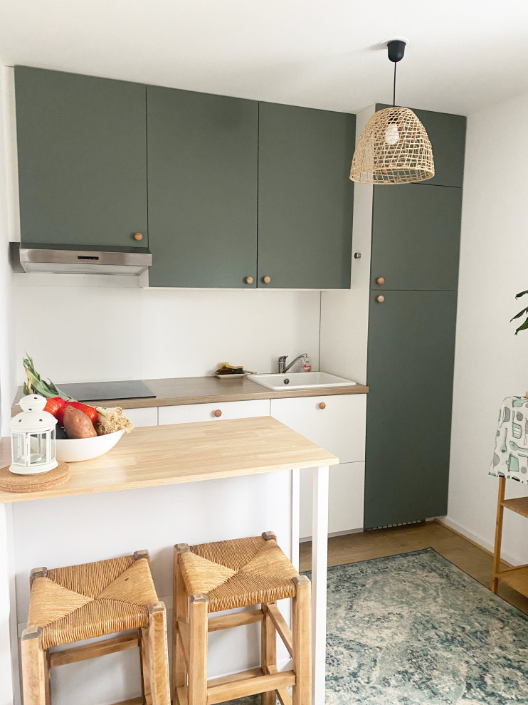 Bild på ett litet minimalistiskt linjärt kök med öppen planlösning, med en enkel diskho, luckor med profilerade fronter, laminatbänkskiva, integrerade vitvaror, laminatgolv och en köksö