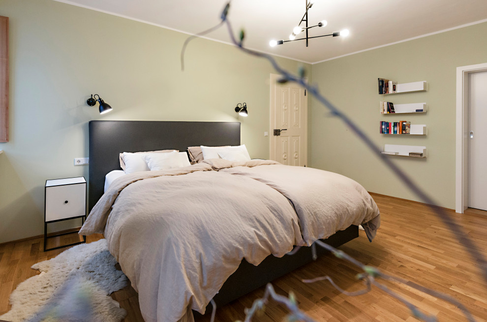 This is an example of a mid-sized contemporary bedroom in Other with green walls, medium hardwood floors and brown floor.