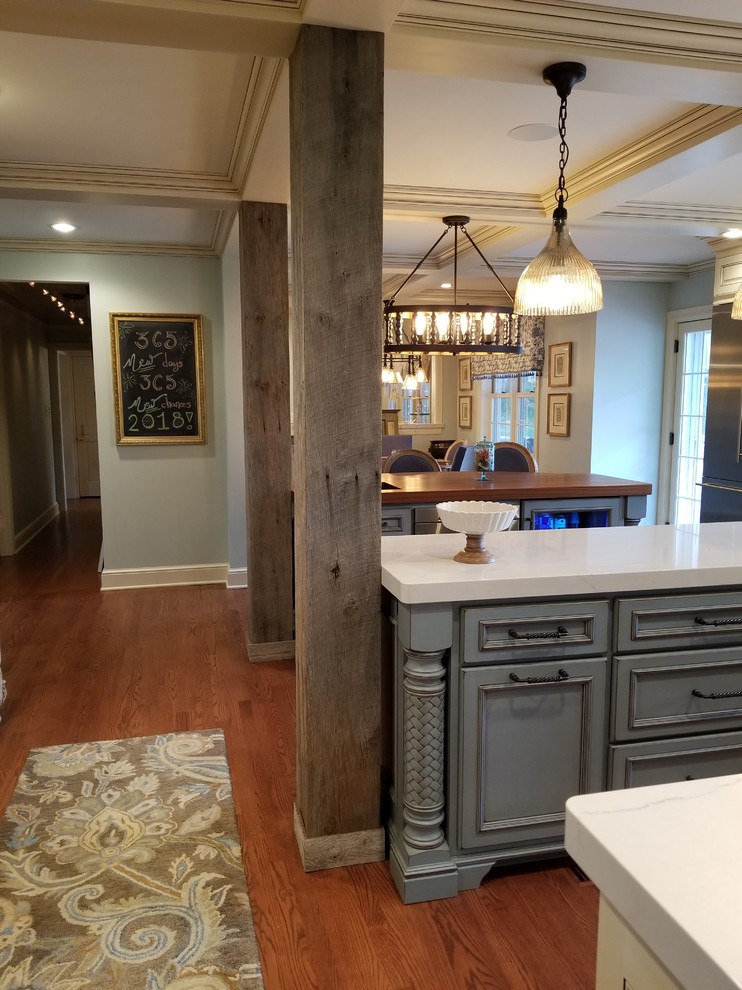 Inspiration for a large country l-shaped eat-in kitchen in Other with a farmhouse sink, recessed-panel cabinets, blue cabinets, quartzite benchtops, white splashback, cement tile splashback, stainless steel appliances, medium hardwood floors, multiple islands, brown floor and white benchtop.