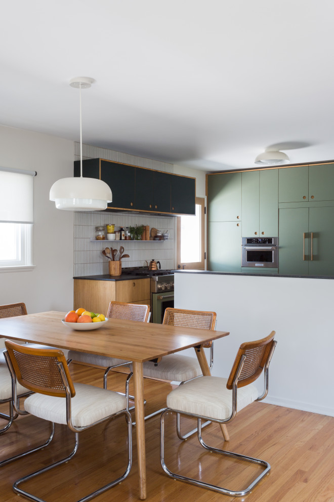 This is an example of a small midcentury l-shaped kitchen in Los Angeles with a submerged sink, flat-panel cabinets, green cabinets, granite worktops, white splashback, ceramic splashback, terrazzo flooring, an island, multi-coloured floors and black worktops.