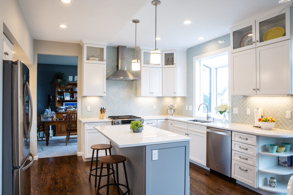 This is an example of a mid-sized transitional u-shaped separate kitchen in Denver with an undermount sink, shaker cabinets, white cabinets, quartz benchtops, blue splashback, ceramic splashback, stainless steel appliances, medium hardwood floors, with island, brown floor and white benchtop.