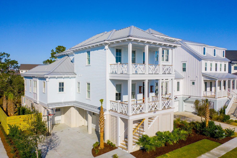 Expansive and blue beach style detached house in Charleston with four floors, a metal roof and a grey roof.