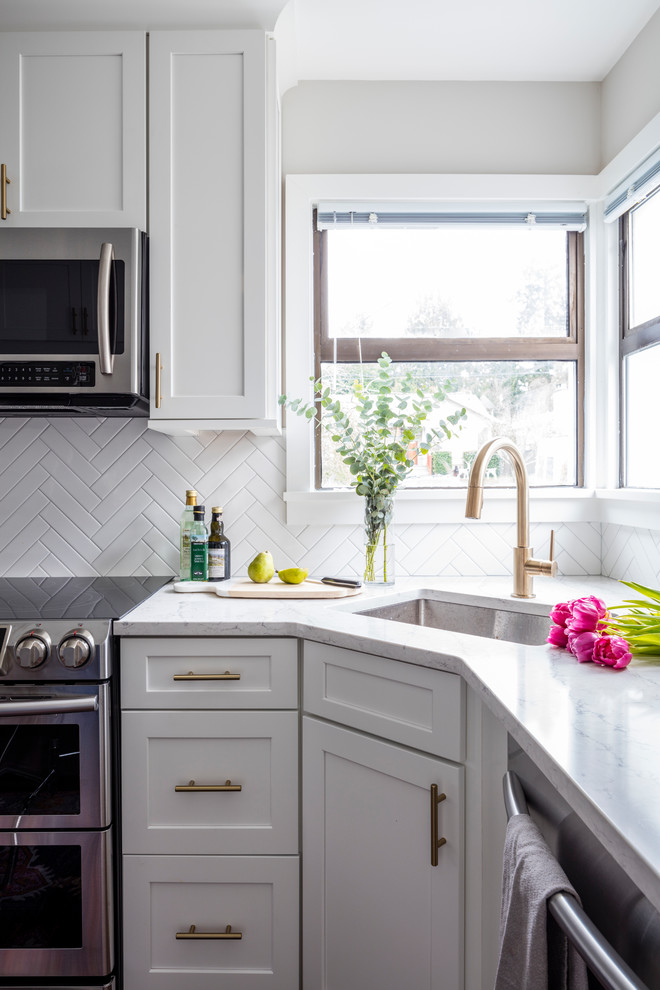 Bild på ett avskilt, litet amerikanskt l-kök, med en undermonterad diskho, skåp i shakerstil, vita skåp, bänkskiva i kvarts, vitt stänkskydd, stänkskydd i keramik, rostfria vitvaror, mellanmörkt trägolv och brunt golv