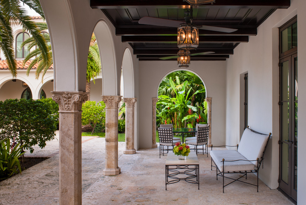 Photo of an expansive mediterranean patio in Miami with tile and a roof extension.