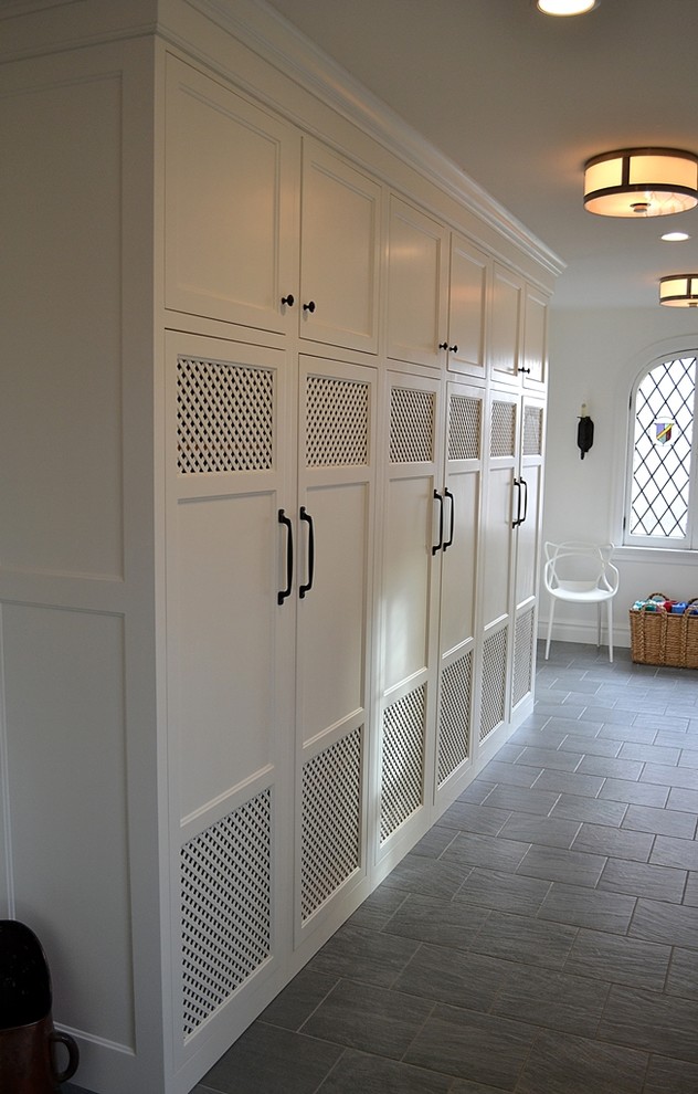Inspiration for a large transitional mudroom in St Louis with white walls and slate floors.