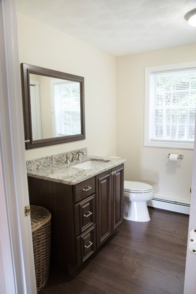 Small modern 3/4 bathroom in Boston with raised-panel cabinets, brown cabinets, a two-piece toilet, yellow walls, medium hardwood floors, granite benchtops, brown floor and an undermount sink.