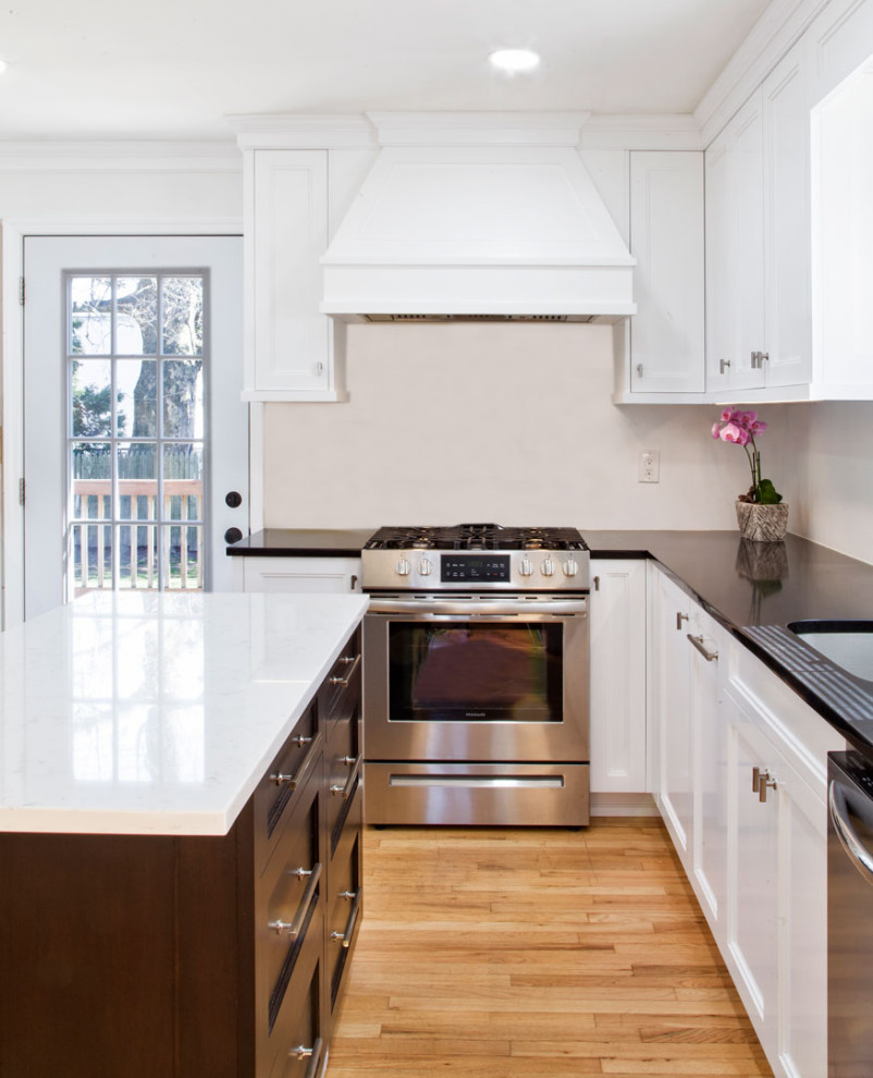 Enclosed kitchen - small transitional u-shaped medium tone wood floor and brown floor enclosed kitchen idea in New York with an integrated sink, shaker cabinets, white cabinets, quartz countertops, white backsplash, stainless steel appliances, an island and black countertops