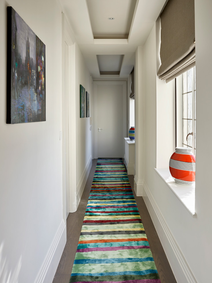 Inspiration for a mid-sized transitional hallway in London with white walls and dark hardwood floors.