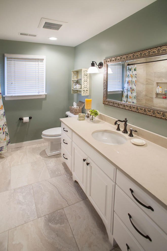 This is an example of a mid-sized transitional kids bathroom in St Louis with white cabinets, an alcove tub, a shower/bathtub combo, a one-piece toilet, beige tile, ceramic tile, green walls, ceramic floors, an undermount sink and onyx benchtops.