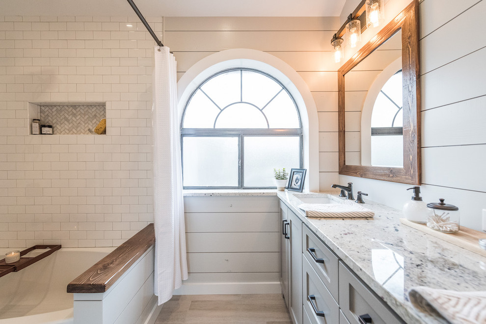 Design ideas for a mid-sized country master bathroom in Dallas with shaker cabinets, grey cabinets, an alcove tub, a shower/bathtub combo, a one-piece toilet, gray tile, porcelain tile, grey walls, porcelain floors, an undermount sink and granite benchtops.