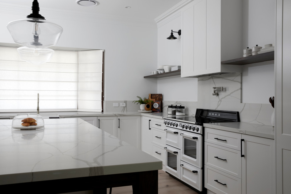 Photo of a shabby-chic style eat-in kitchen in Sydney with a farmhouse sink, quartz benchtops, white splashback, engineered quartz splashback, white appliances, light hardwood floors, with island, beige floor and white benchtop.