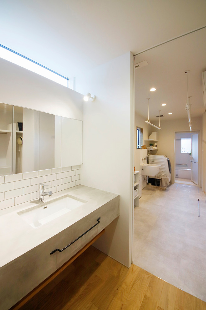 Photo of a modern powder room in Other with open cabinets, grey cabinets, white tile, subway tile, white walls, medium hardwood floors, an undermount sink, grey benchtops, a freestanding vanity and wallpaper.