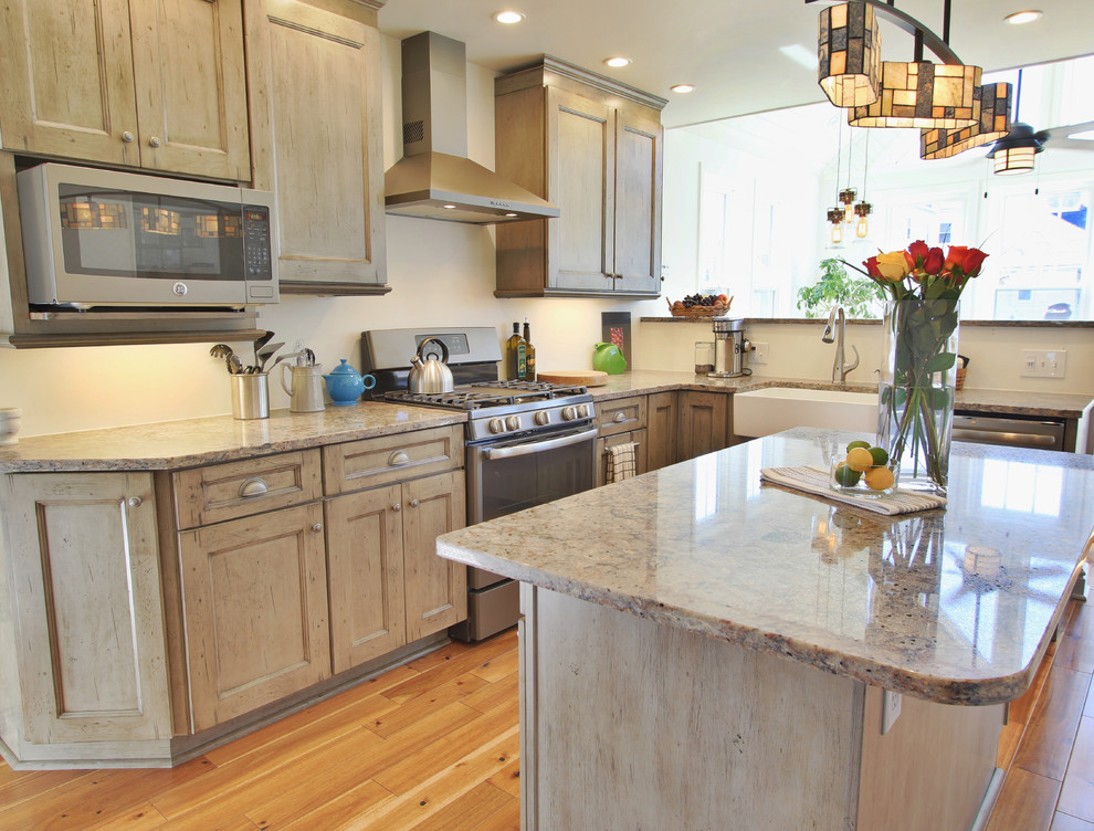 Example of a mid-sized light wood floor eat-in kitchen design with a farmhouse sink, distressed cabinets, granite countertops, stainless steel appliances and an island