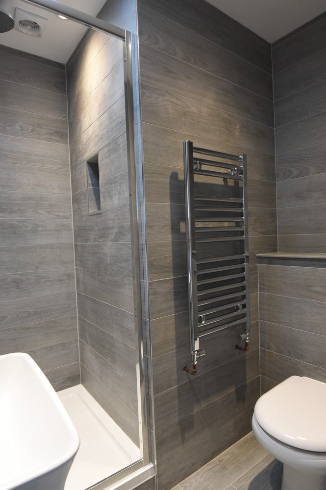 Inspiration for a mid-sized modern master bathroom in London with a curbless shower, a one-piece toilet, gray tile, ceramic tile, grey walls, ceramic floors, a wall-mount sink and tile benchtops.