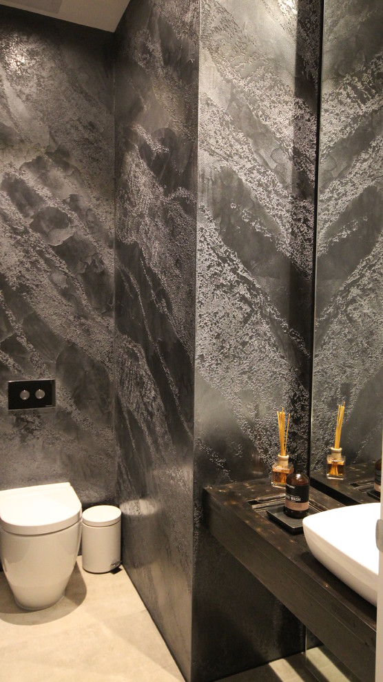 Cette image montre un WC suspendu minimaliste en bois foncé avec un carrelage beige, un mur noir et un plan de toilette en bois.