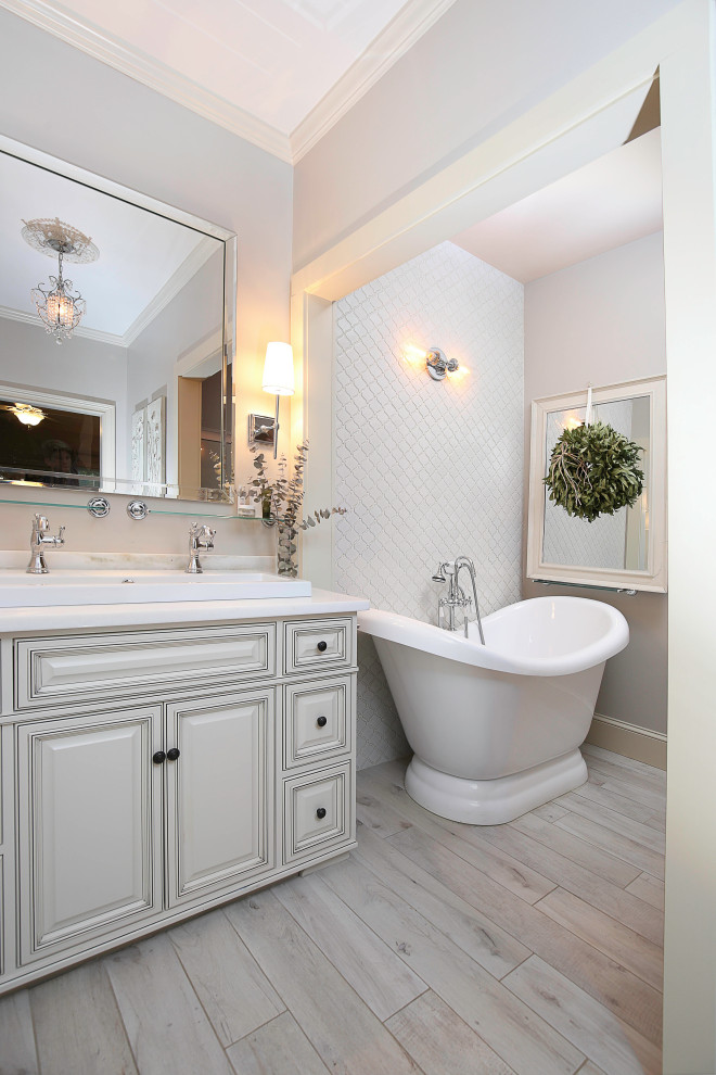 Inspiration for a small traditional master bathroom in Other with raised-panel cabinets, distressed cabinets, a freestanding tub, gray tile, ceramic tile, grey walls, wood-look tile, a drop-in sink, engineered quartz benchtops, grey floor, white benchtops, a single vanity and a built-in vanity.
