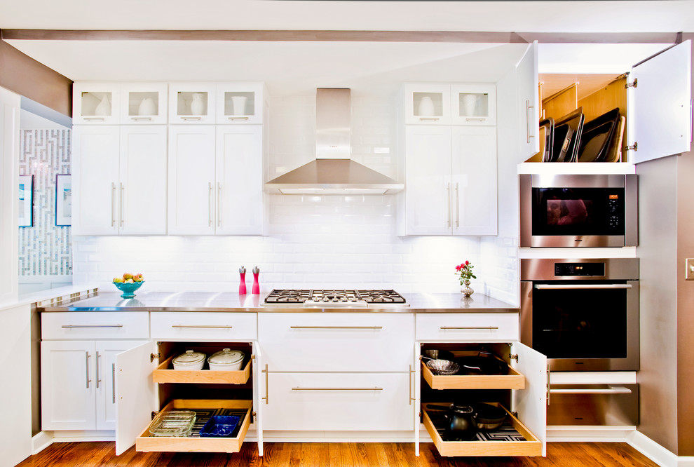 This is an example of a mid-sized transitional single-wall kitchen in Chicago with shaker cabinets, white cabinets, white splashback, subway tile splashback, stainless steel appliances, stainless steel benchtops and medium hardwood floors.