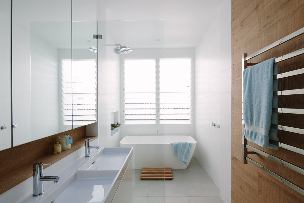 Design ideas for a mid-sized contemporary master bathroom in Sydney with flat-panel cabinets, white cabinets, a freestanding tub, an open shower, white tile, white walls, an integrated sink, white floor and an open shower.