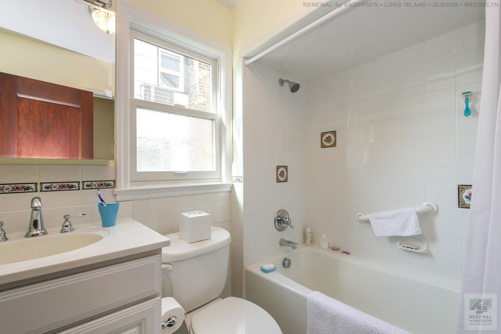 Medium sized bathroom in New York with white cabinets, an alcove bath, a shower/bath combination, a two-piece toilet, white tiles, yellow walls, ceramic flooring, an integrated sink, engineered stone worktops, white floors, a shower curtain, white worktops, a single sink and a freestanding vanity unit.