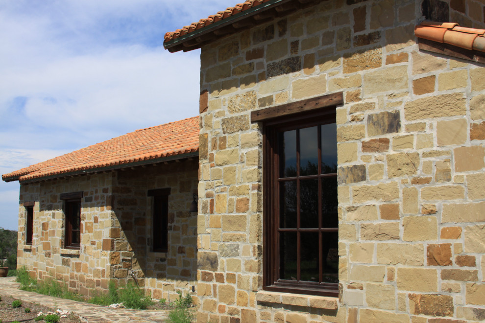 Photo of a large mediterranean two floor detached house in Austin with stone cladding, a pitched roof, a tiled roof and a red roof.