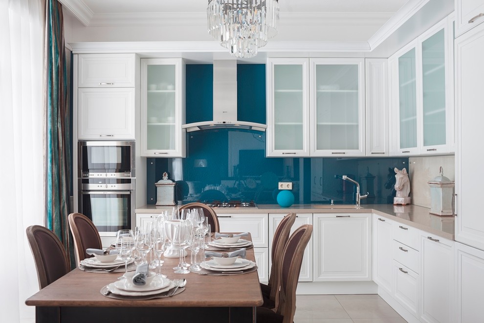 Mid-sized traditional l-shaped eat-in kitchen in Moscow with an undermount sink, raised-panel cabinets, white cabinets, solid surface benchtops, blue splashback, glass sheet splashback, stainless steel appliances, porcelain floors, no island and beige floor.