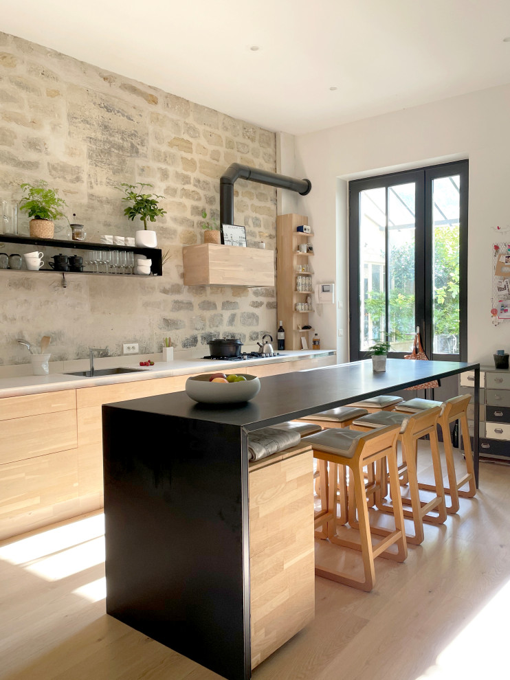 Immagine di una grande cucina industriale con ante in legno chiaro, elettrodomestici da incasso, parquet chiaro e top bianco