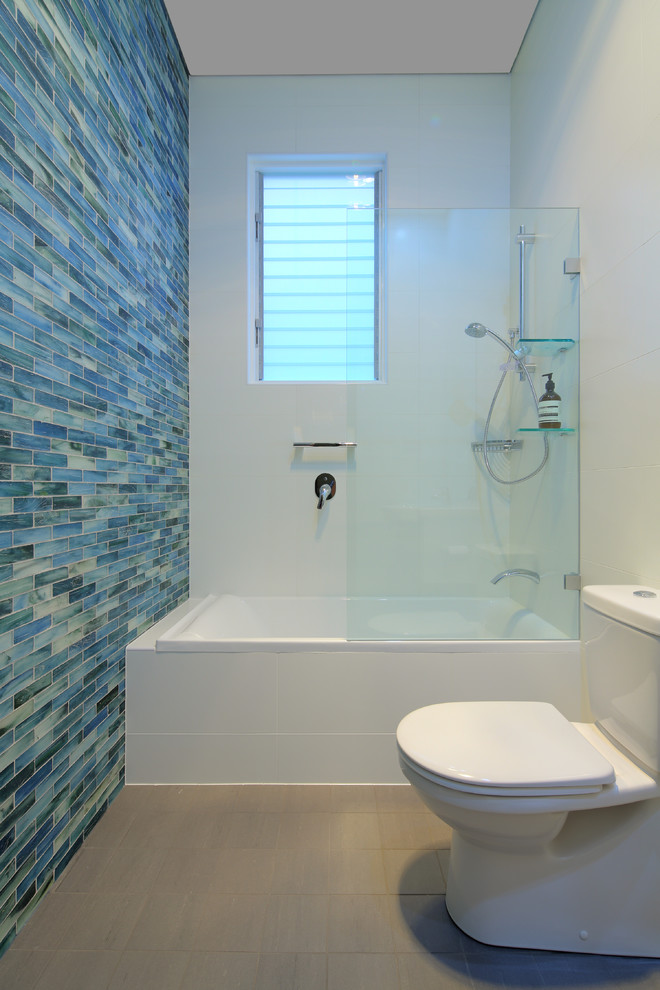 This is an example of a contemporary master bathroom in Sydney with glass tile, a drop-in tub, a shower/bathtub combo, white walls and blue tile.