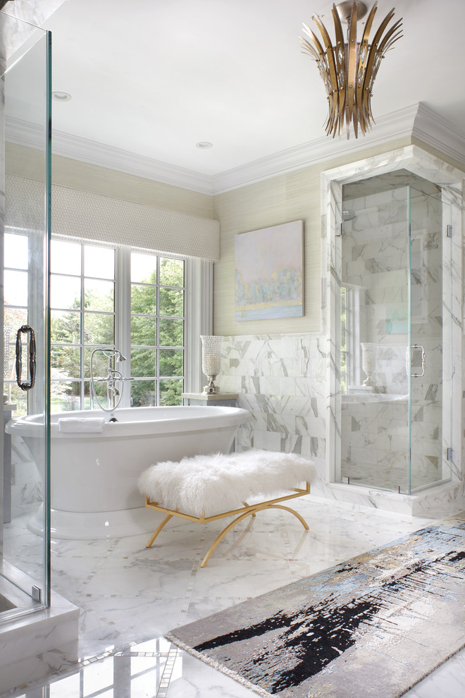 Photo of a large traditional master bathroom in New York with a freestanding tub, white tile, beige walls, a hinged shower door, recessed-panel cabinets, white cabinets, a corner shower, a bidet, marble, marble floors, an undermount sink, engineered quartz benchtops and white floor.