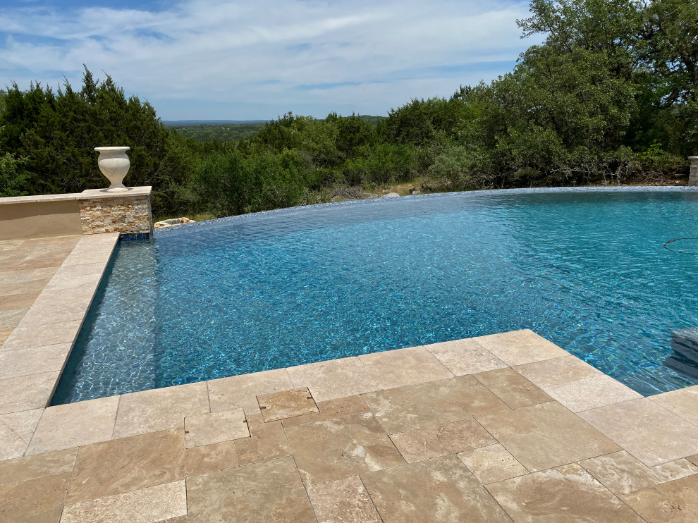 Design ideas for an expansive modern backyard custom-shaped infinity pool in Austin with with privacy feature and decking.