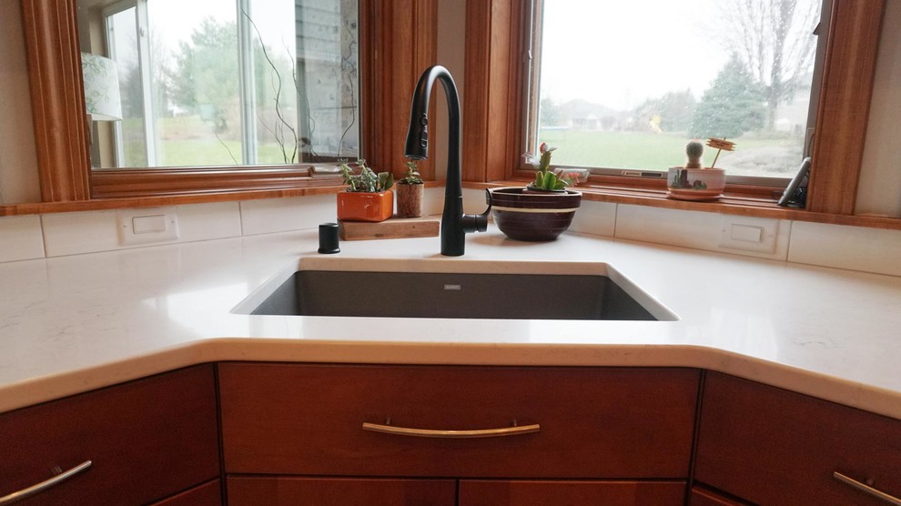 Large transitional l-shaped medium tone wood floor open concept kitchen photo with an undermount sink, recessed-panel cabinets, brown cabinets, white backsplash, subway tile backsplash, stainless steel appliances, an island and white countertops