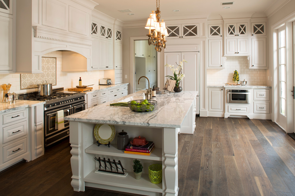 Design ideas for an expansive traditional l-shaped kitchen in Houston with an undermount sink, raised-panel cabinets, white cabinets, marble benchtops, white splashback, subway tile splashback, panelled appliances, dark hardwood floors, with island, black floor and white benchtop.