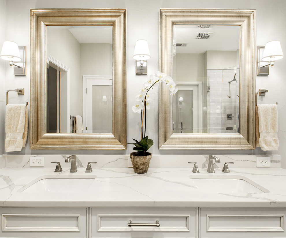 This is an example of a mid-sized transitional master bathroom in Dallas with recessed-panel cabinets, white cabinets, a corner shower, a two-piece toilet, gray tile, marble, grey walls, porcelain floors, an undermount sink, engineered quartz benchtops, brown floor, a hinged shower door and white benchtops.