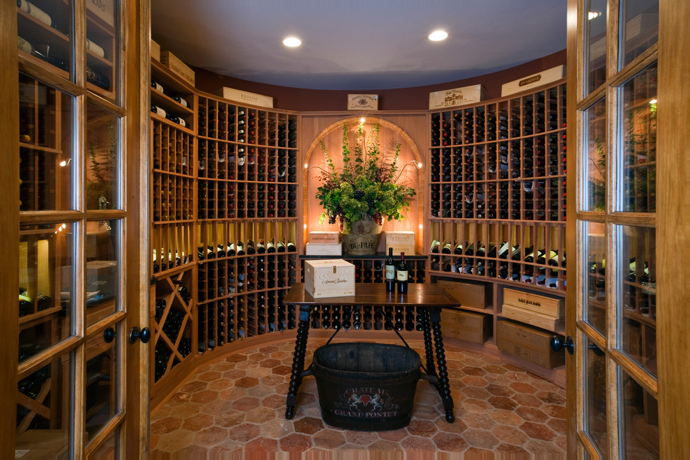 This is an example of an expansive traditional wine cellar in Chicago with terra-cotta floors and display racks.