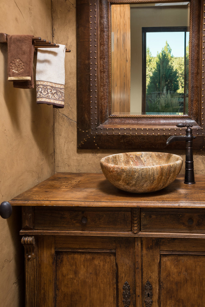 This is an example of a small country powder room in Other with a vessel sink, furniture-like cabinets, wood benchtops, dark wood cabinets and brown benchtops.